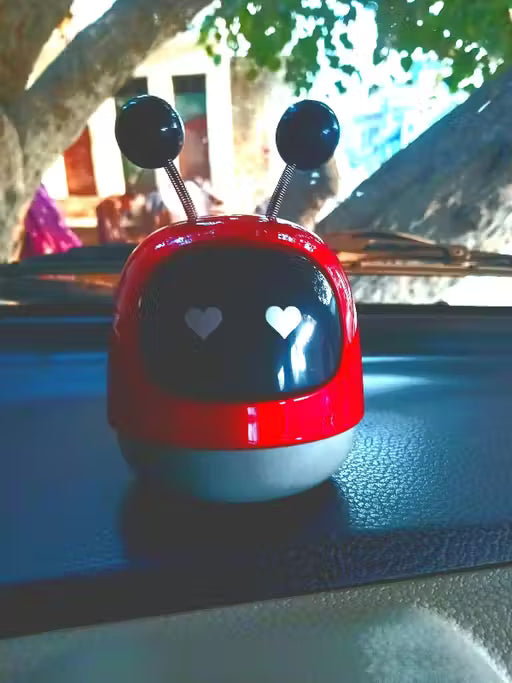 Mini Robot Car Perfume-Red and white toy with heart designs on a car dashboard