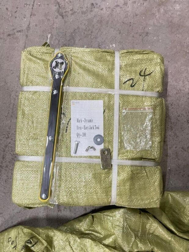 Green tarpaulin package with tools on a concrete floor