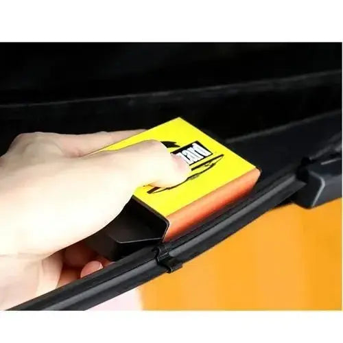 Hand holding a yellow car wiper blade with a brand logo against a black background