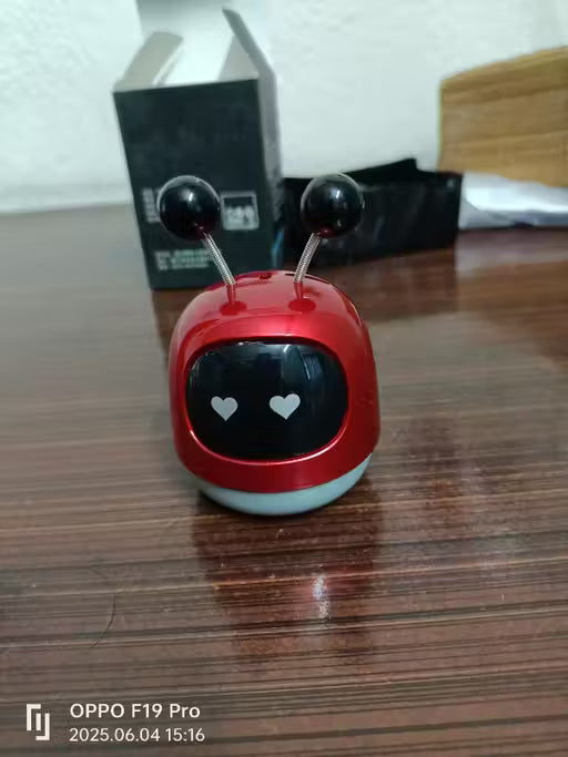 Mini Robot Car Perfume-Small red robot toy with black eyes on a wooden surface