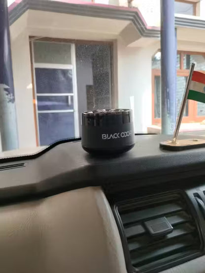 Black container with 'Black Odor' branding on a car dashboard.