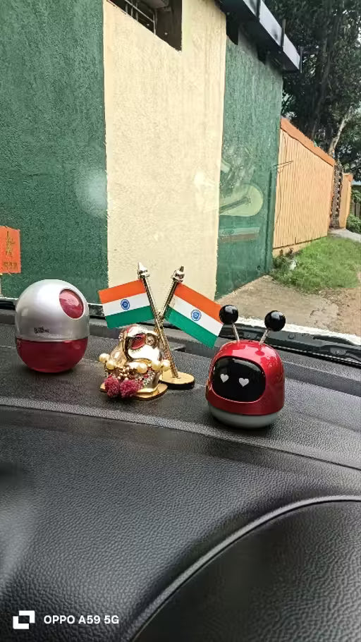 Mini Robot Car Perfume-Car dashboard with decorative items including a small flag and a red and silver object.
