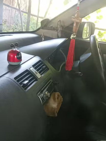 Mini Robot Car Perfume-Car dashboard with a red car accessory and tassel hanging from the rearview mirror.