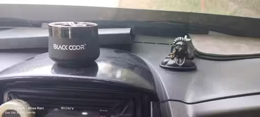 Car air freshener with 'Black Odor' branding on a car dashboard.